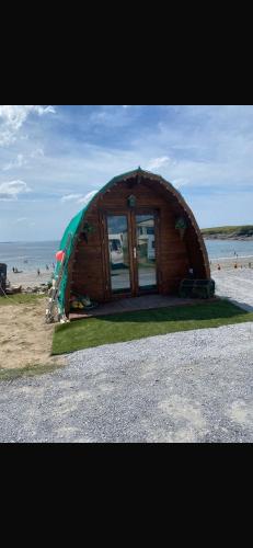a small wooden house on the beach with the ocean at Glamping Pod in Miltown Malbay