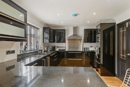 a kitchen with black cabinets and a counter top at 7 Bed Coastal Villa - Private Heated Pool, Sauna, Parking in Filey