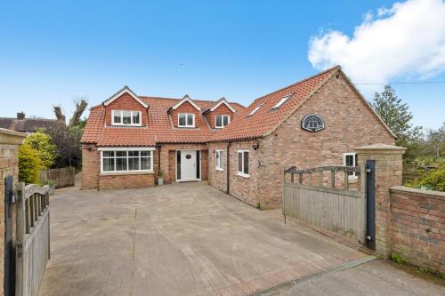 a brick house with a driveway in front of it at 7 Bed Coastal Villa - Private Heated Pool, Sauna, Parking in Filey