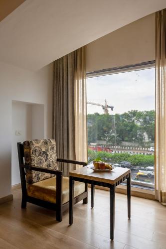 a living room with a table and a chair and a window at Arch The Lohias in New Delhi