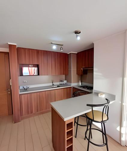a kitchen with wooden cabinets and a table and chairs at Condominio en el Centro de Calama in Calama