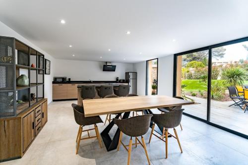 a kitchen and dining room with a wooden table and chairs at Appart HOTEL 3 Chambres - parking - clim in Saint-Raphaël