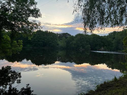Una vista de un lago con árboles y una puesta de sol. en LA Combe, en Confolens