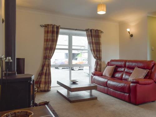 a living room with a red leather couch and a sliding glass door at The Barn in Fintry