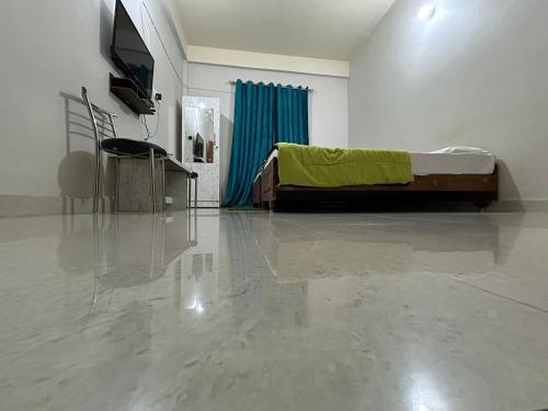 a room with a bed and a television and a concrete floor at Kaziranga Balaji Homestay in Kāziranga