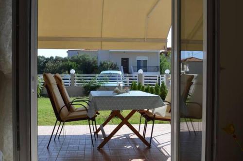 a table and chairs sitting on a patio with an umbrella at 2 Bed-Sleeps4-Garden-Parking-Pets-AirCon in Nikiti