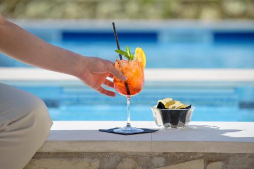 a person holding a cocktail in a glass next to a pool at Terra Dei Limoni in Noto Marina
