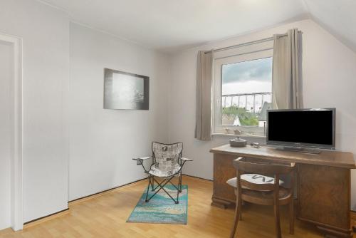 a living room with a desk with a television and a chair at Ferienwohnung Ruhepol, 75qm in Vellmar