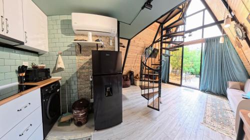 een keuken met een zwarte koelkast en een wenteltrap bij Cottage Tetra Kutaisi Tskaltubo in Khomuli
