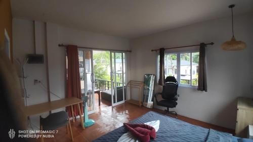 a bedroom with a bed and a desk and two windows at Green moonVillage in Ban Nok