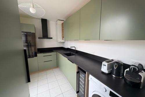 une cuisine avec des placards verts et un comptoir noir dans l'établissement Spacious duplex in the heart of Bordeaux, à Bordeaux