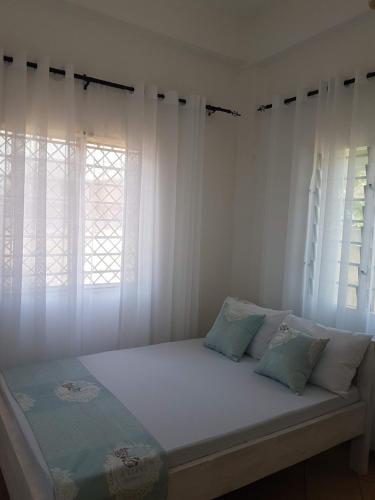 a bed in a room with white curtains at L & C Chinese Studio in Diani Beach