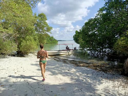 a woman walking on a beach next to a boat at Fins Zanzibar Dolphins Tours in Dimbani