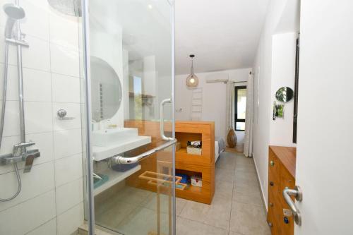 Un baño con lavabo y ducha de cristal. en Le Bergamote, en Riambel