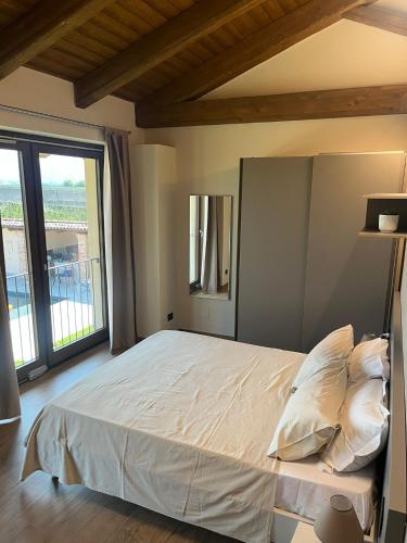 a bedroom with a white bed with a large window at La Porta delle Meraviglie in Saluzzo
