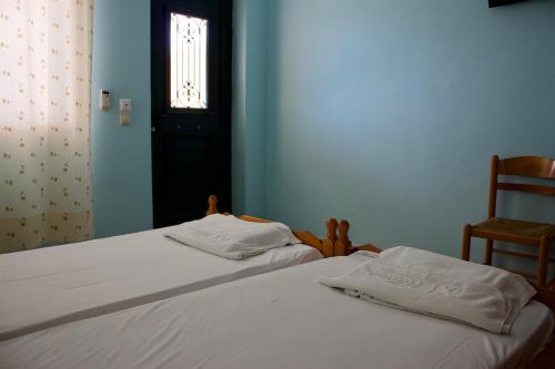 two beds in a bedroom with a window and a chair at Xi Village in Xi