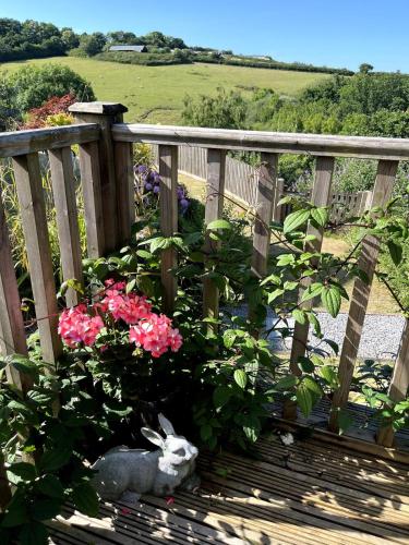 a rabbit sitting on a deck with flowers at The Hutch Devon in Longdown
