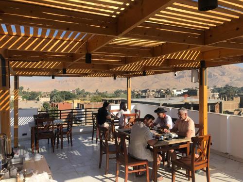 a group of people sitting at tables on a patio at Farida Habu Palace Hotel luxor in Al Aqālitah