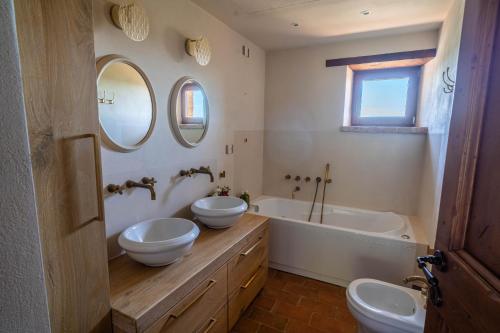 a bathroom with two sinks and a tub and two mirrors at Agriturismo Sole in Trequanda