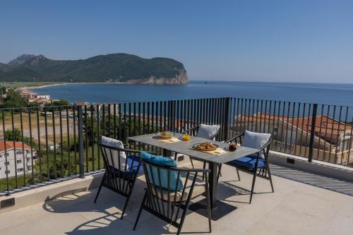 a table and chairs on a balcony with a view of the ocean at Hotel AQUILO in Petrovac na Moru