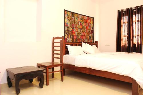 a bedroom with a bed and a chair and a painting at Relax Inn Jaisalmer in Jaisalmer