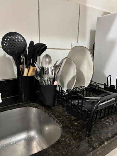 a kitchen counter with dishes in a drying rack next to a sink at Térreo, sem escadas, com WI-FI, a 15 minutos do centro in Brasilia