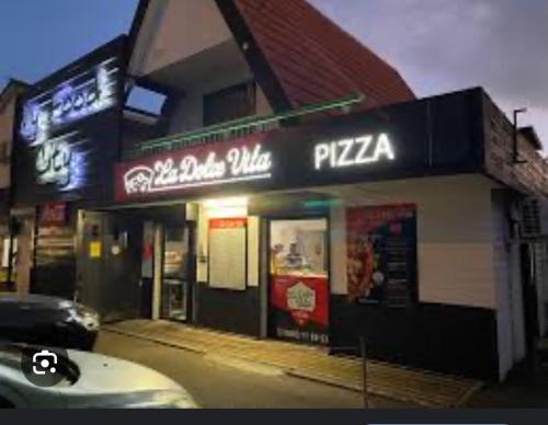 a pizza shop with a car parked in front of it at ti sable appartement à 5 minutes de la mer in Saint-Joseph