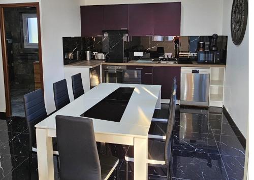 - une cuisine avec une table et des chaises blanches dans l'établissement Appartement et son jacuzzi, à Saint-Cézaire-sur-Siagne