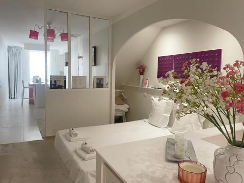 a white room with a vase of flowers on a table at "Rose" Atypique, clim, coeur du Quartier Haut in Sète
