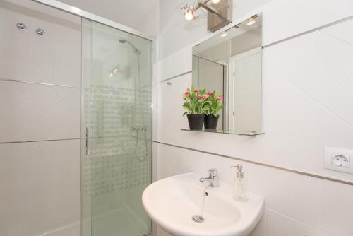 a white bathroom with a sink and a shower at The Zentral Suites & Apartments in Seville