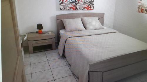 a small bedroom with a bed and a night stand at Embruns 2 in Le Moule