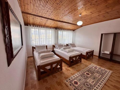 a living room with two beds and a wooden ceiling at Zholi Guest House in Gjirokastër