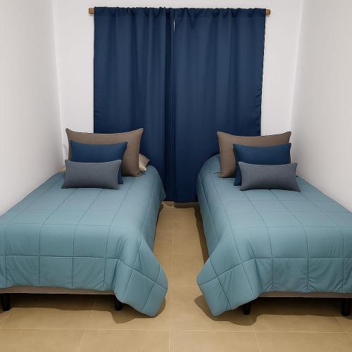 two beds in a room with blue curtains at Vista Malargüe House in Malargüe