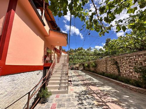 a building with stairs next to a brick wall at Zholi Guest House in Gjirokastër
