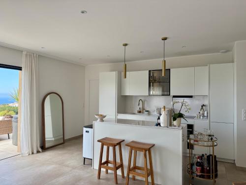 a kitchen with white cabinets and a bar with stools at Appartement standing grande terrasse vue mer in Monticello