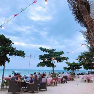 a group of people sitting at tables on the beach at Haad Yao Bayview Resort in Haad Yao
