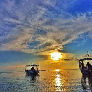 two boats in the water with the sunset in the background at Haad Yao Bayview Resort in Haad Yao