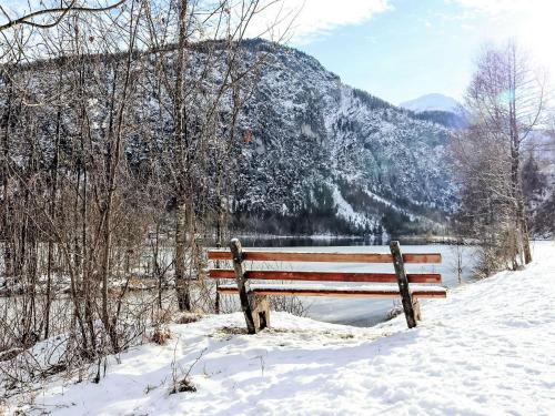 a wooden bench sitting in the snow in front of a mountain at Apartment Kesselboden by Interhome in Grünau im Almtal