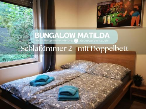 a bed with two blue pillows on top of it at Bungalow Matilda in Lauchhammer