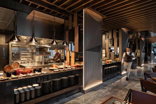 a restaurant with people preparing food in a kitchen at Swissôtel Living Jakarta Mega Kuningan in Jakarta