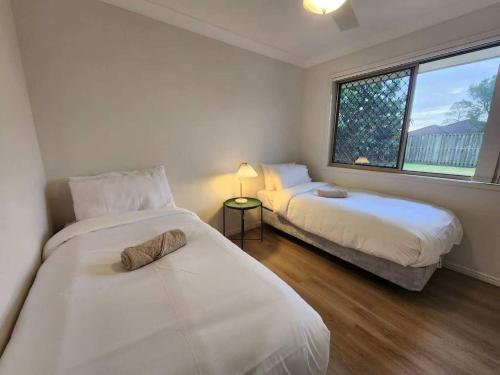 a bedroom with two beds and a window at Simple and Comfy Family Home between BNE and Ipswich in Bellbird Park