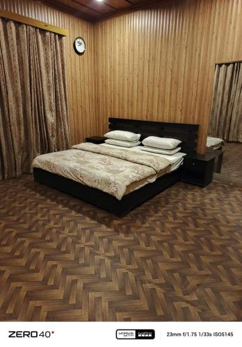 a bedroom with a bed and a clock on the wall at Forest Valley Cottages Kalam by Khan Familia Travels in Kalām