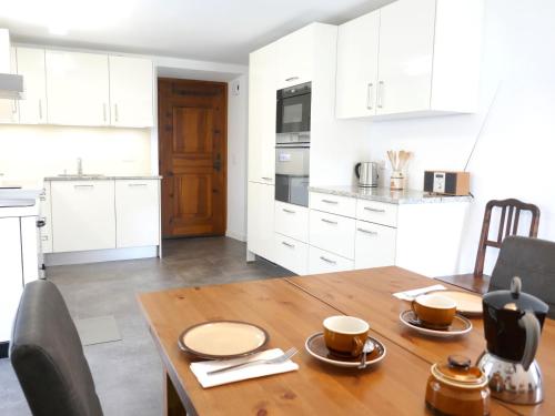 a kitchen with a wooden table and white cabinets at Holiday Home Casa Calanca by Interhome in Grono