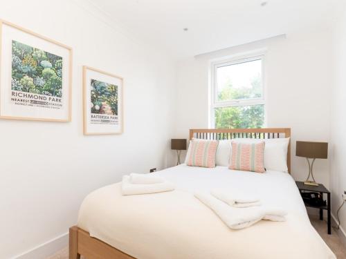a white bedroom with a large white bed with a window at Pass the Keys Stunning 4Bed Oasis in Kingston With Parking in Kingston upon Thames