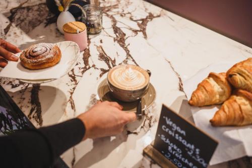 a person is taking a drink on a table with pastries at The Circus Living in Berlin