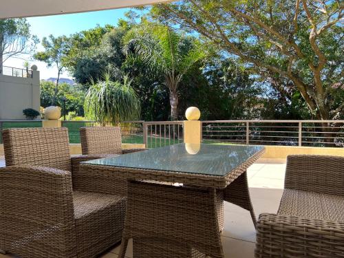 a glass table and chairs on a patio at Bay Ridge Luxury Apartment, Ballito in Ballito