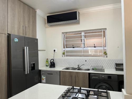 a kitchen with a stainless steel refrigerator and a sink at Bay Ridge Luxury Apartment, Ballito in Ballito