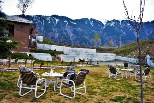 a group of chairs and tables in a field at Forest Valley Cottages Kalam by Khan Familia Travels in Kalām
