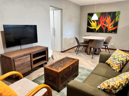 a living room with a television and a table at Monstera Apartments in Paramaribo
