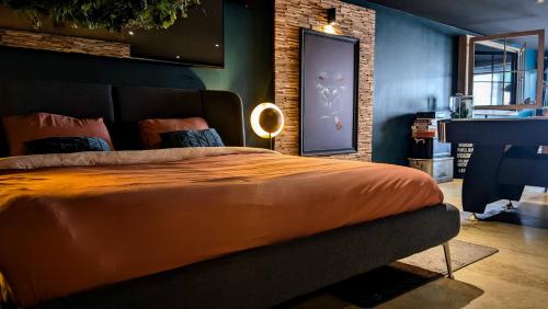 a bedroom with a large bed with an orange blanket at Le Theux Toit - Escapade romantique et Wellness in Theux